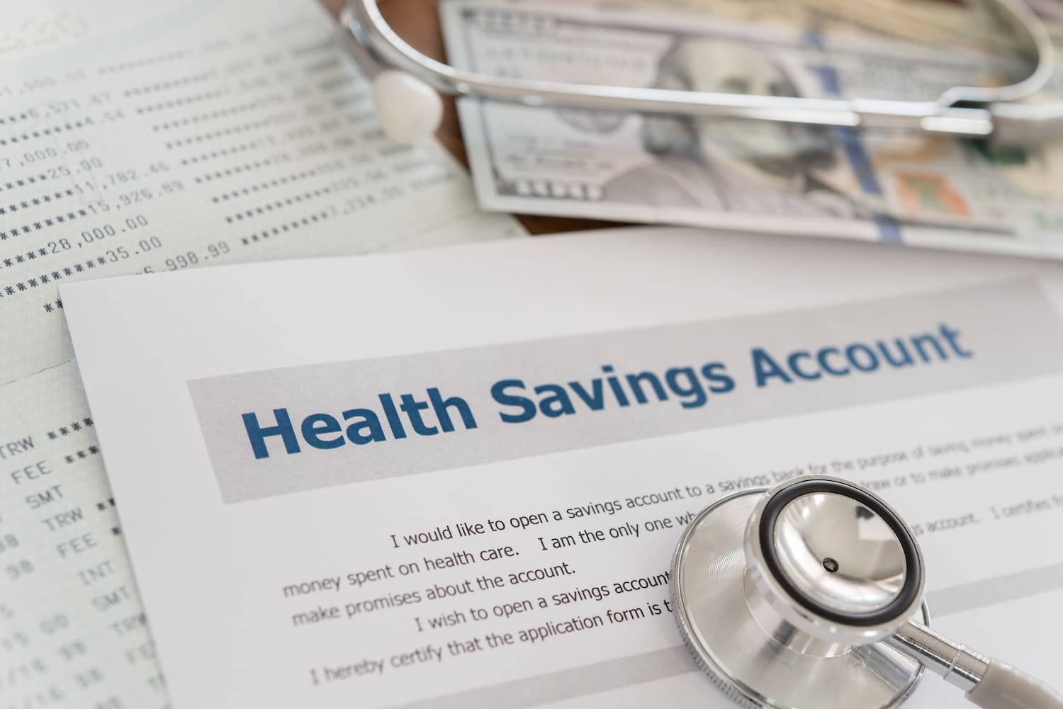 health savings account HSA concept with application form, dollar money, stethoscope, bank account on desk.