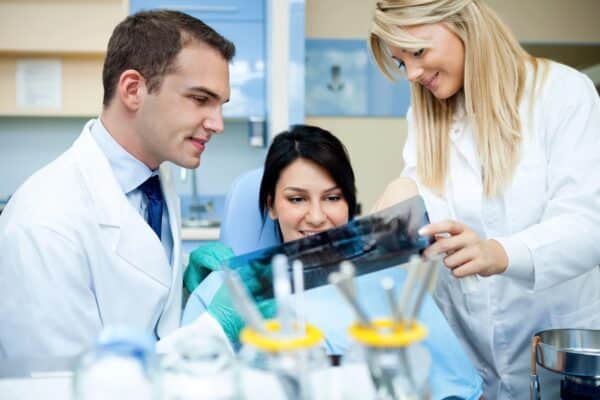 Young dentist with assistant and patient