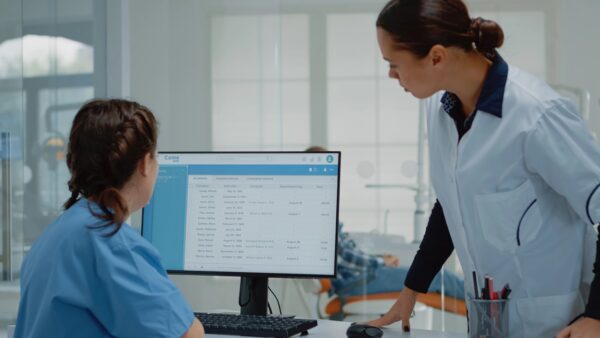 Professional dentist preparing for consultation using x ray from assistant desk at oral clinic. Stomatology nurse working on computer while orthodontist examining patient toothcare