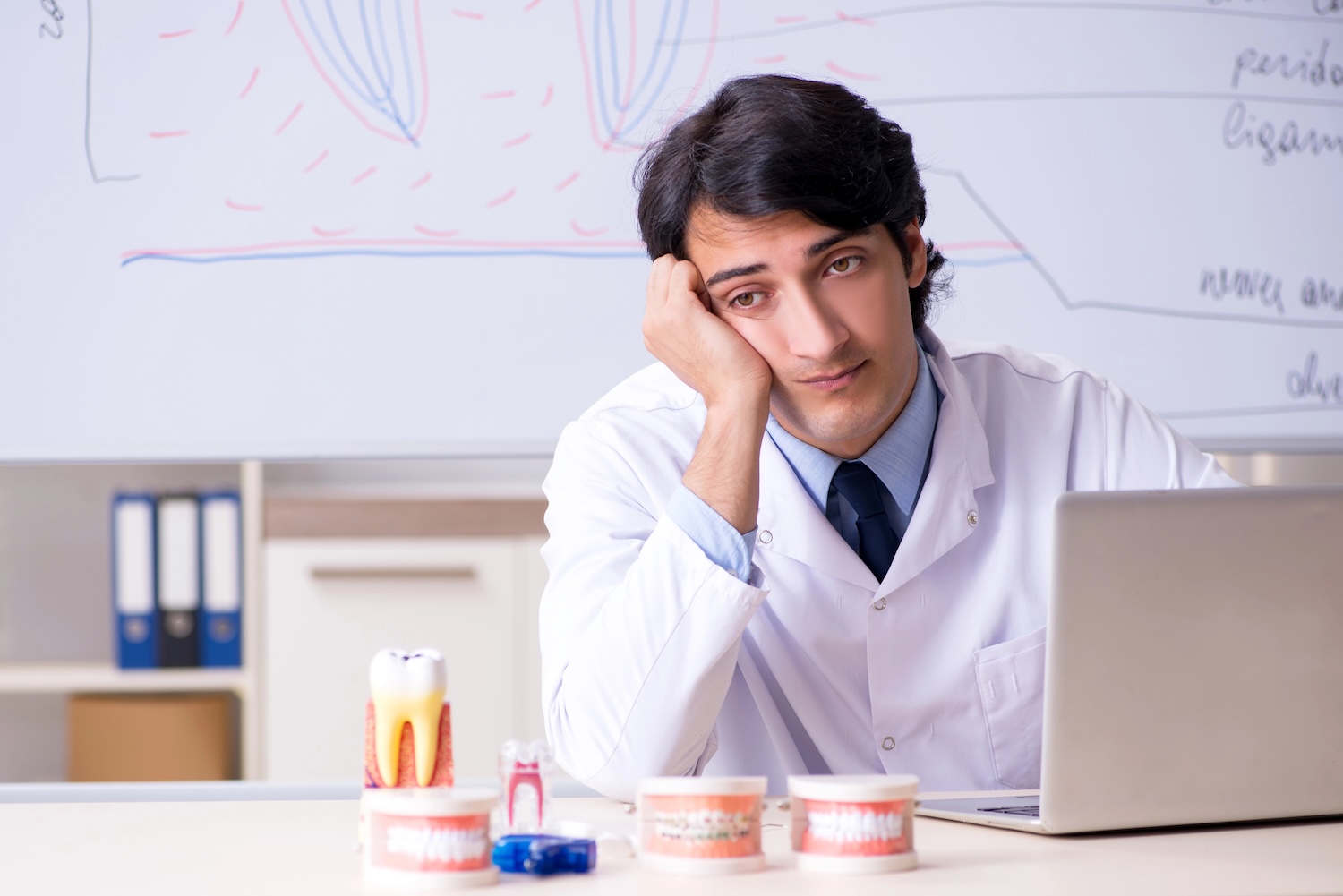 Young sad dentist in front of the whiteboard