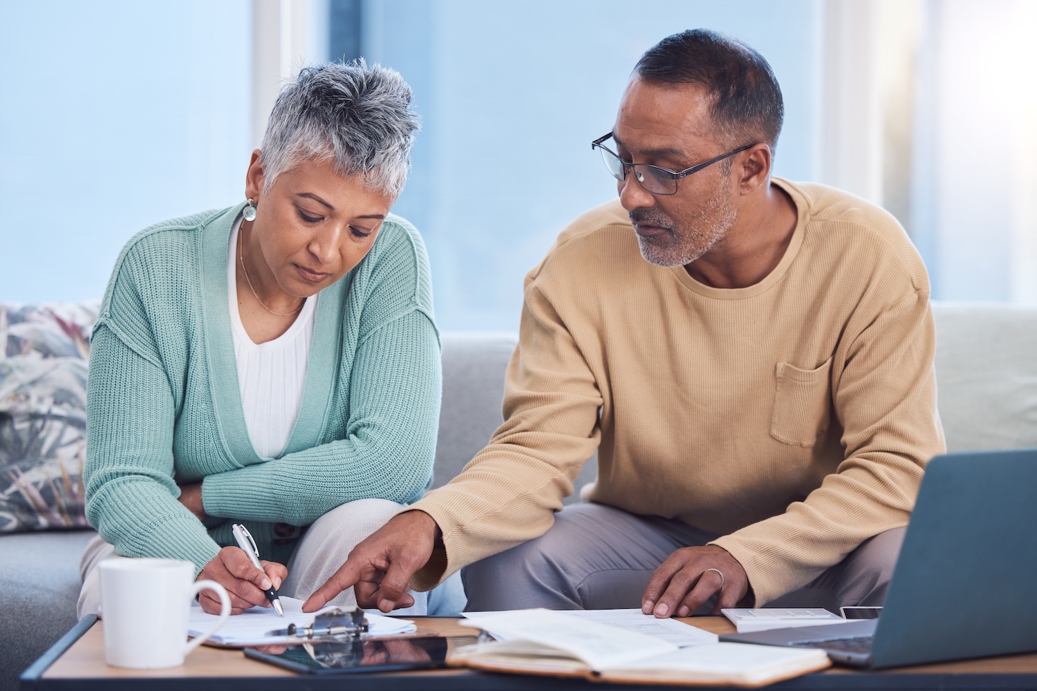 Senior black dentist couple looking at retirement planning docs on laptop
