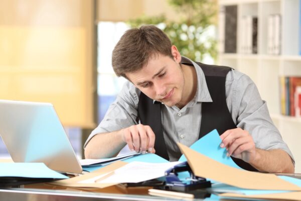 Man with disorganized desk searching lost documents at office