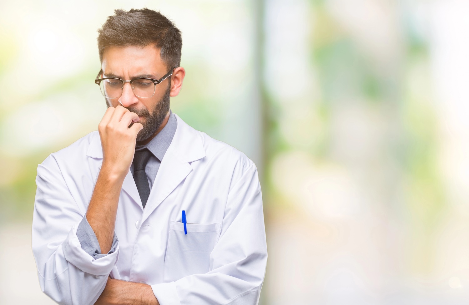 Adult hispanic dentist man wearing white coat over isolated background looking stressed and nervous with hands on mouth biting nails. Anxiety problem.