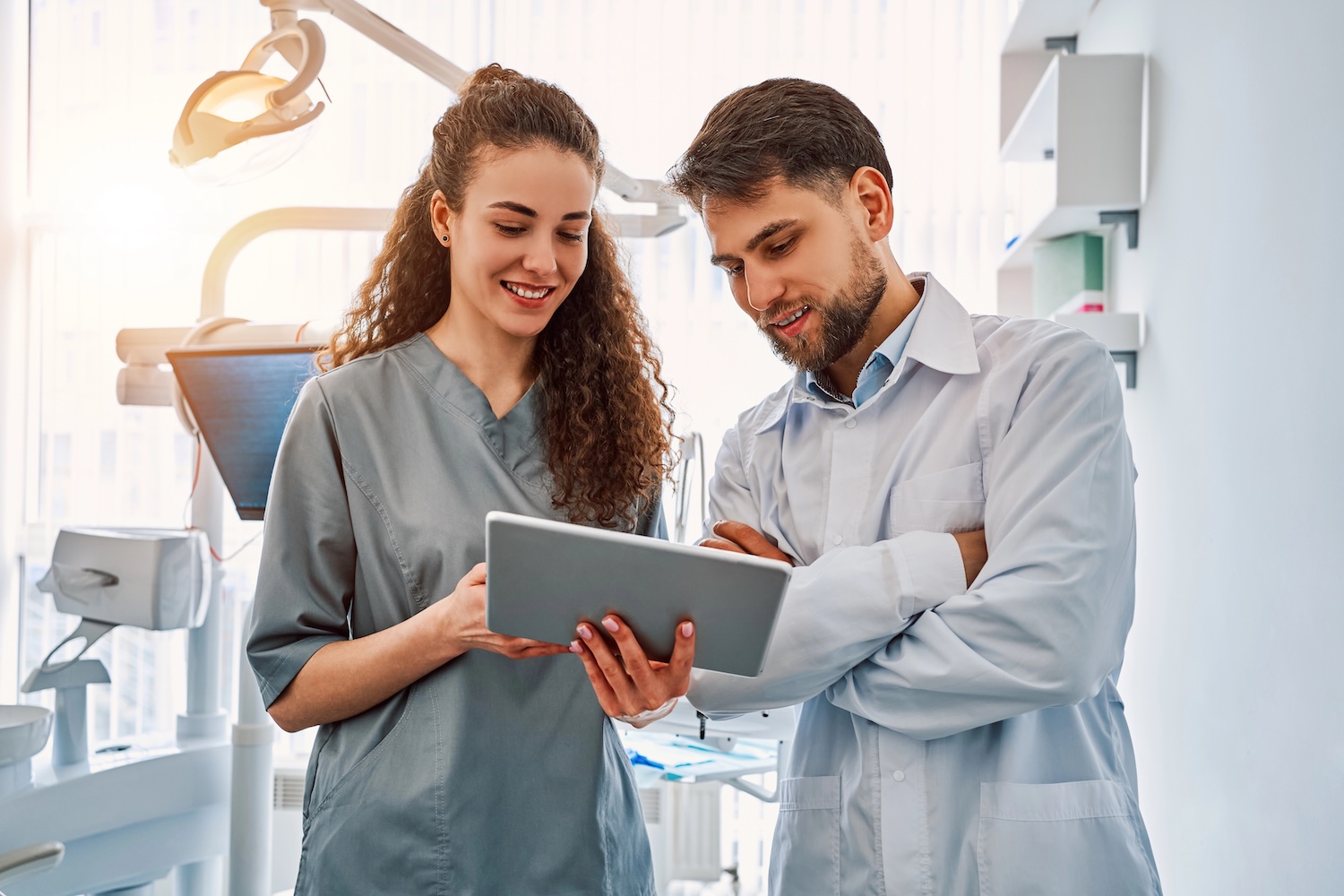 Two dentist are standing in a dental office and looking at a tablet. Medicine, dentistry. Close-up portrait.
