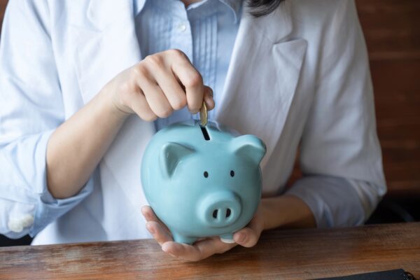 Dentist putting coins into blue piggy bank.