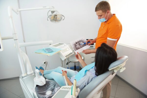 Male stomatologist showing radiography scan of jaw to woman