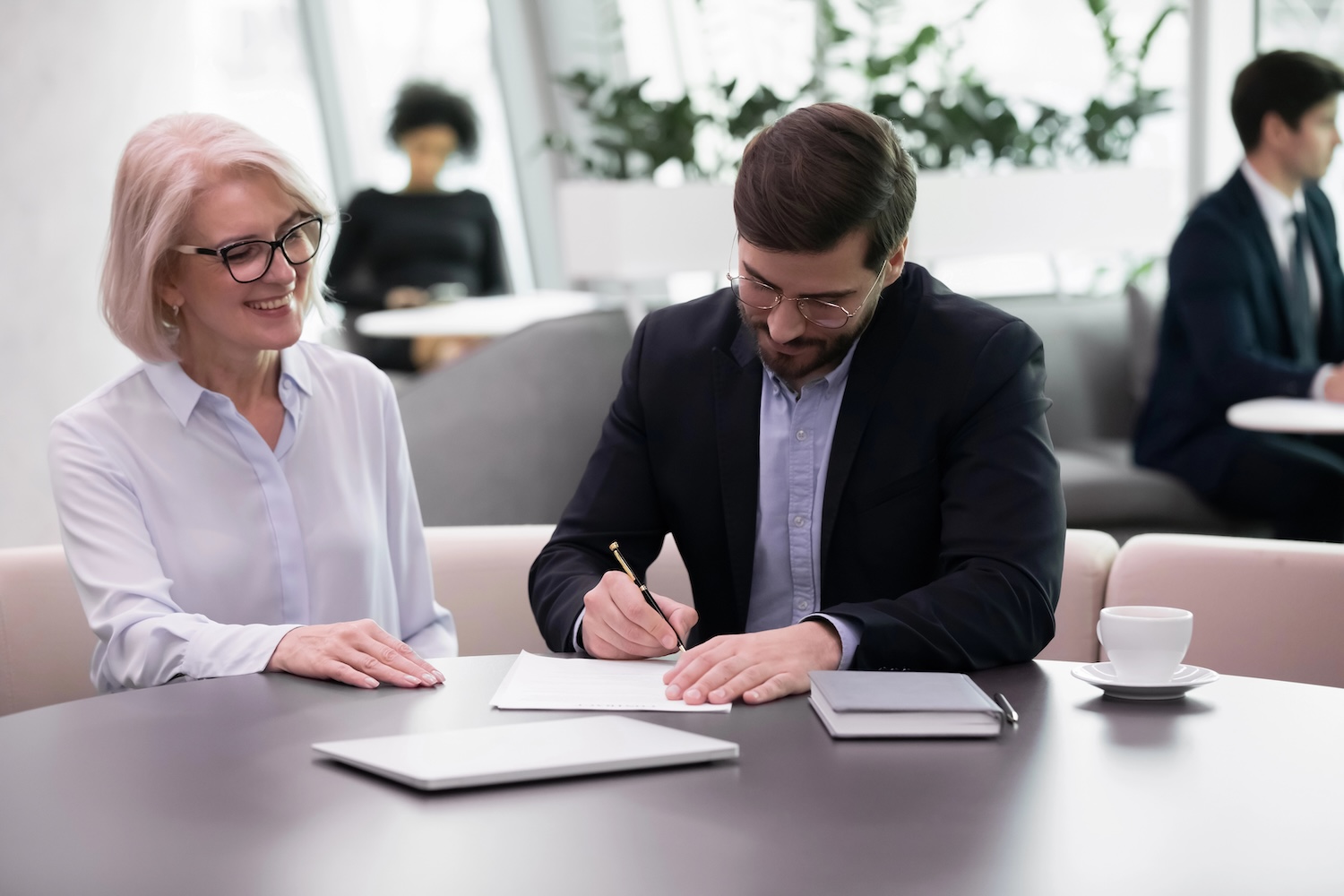 Middle-aged man filling form take bank application, partners making financial deal during meeting in bank